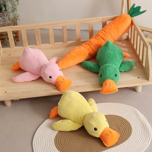 Colorful plush ducks and carrot toy on a wooden tray.