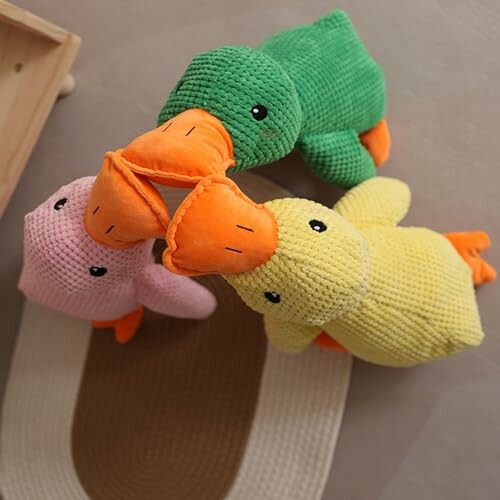 Three plush duck toys in green, yellow, and pink arranged in a circle.